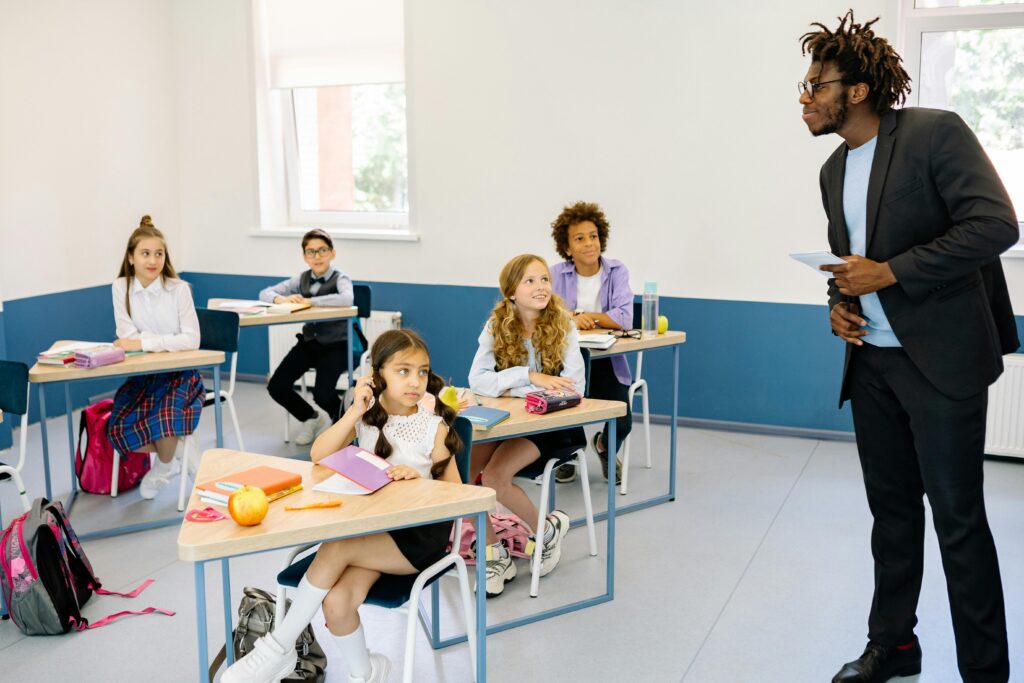 Students attentively listening to a teacher in a modern classroom setting.