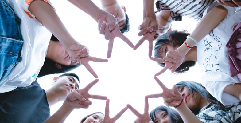 A circle of friends forming a star shape with fingers, symbolizing unity and teamwork.