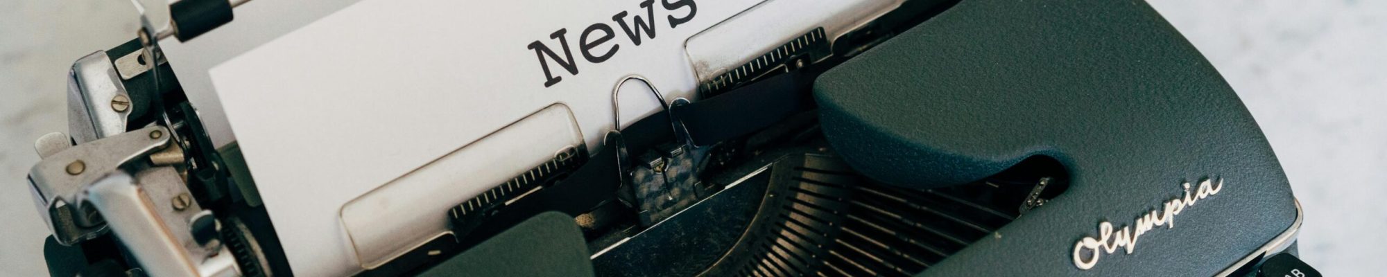Close-up of an antique typewriter with 'News' on paper.